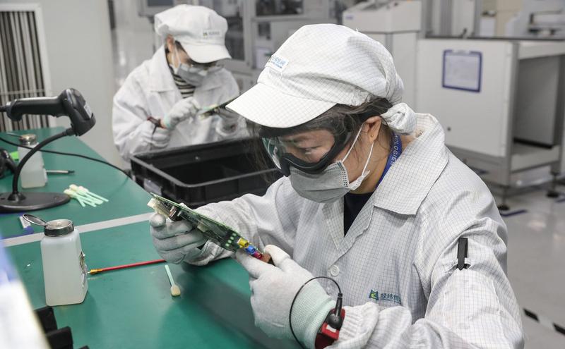 中国江苏省南通市一家电子厂的工人戴着口罩复工。
