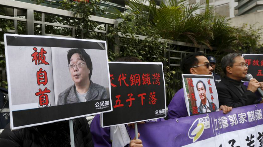 香港抗議者在北京駐香港機構中聯辦前手舉銅鑼灣書店失蹤老闆桂民海的照片。（美國之音）