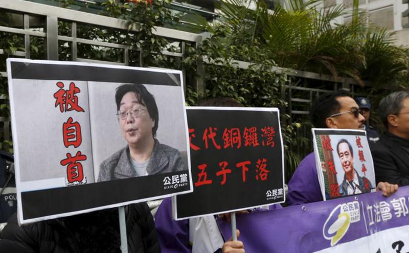 香港抗议者在北京驻香港机构中联办前手举铜锣湾书店失踪老板桂民海的照片。（美国之音）