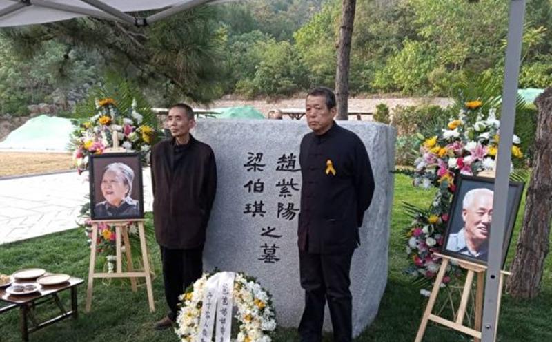 2019年10月18日，赵紫阳夫妇墓碑前摆放着出席骨灰安葬仪式的亲友们献的鲜花。赵紫阳之子赵二军（右）立于碑前。（美国之音）