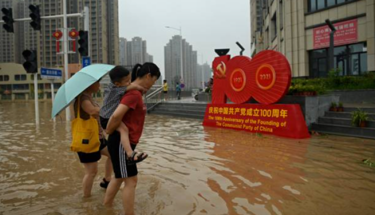 郑州市民淌水路过中共建党百年的宣传牌