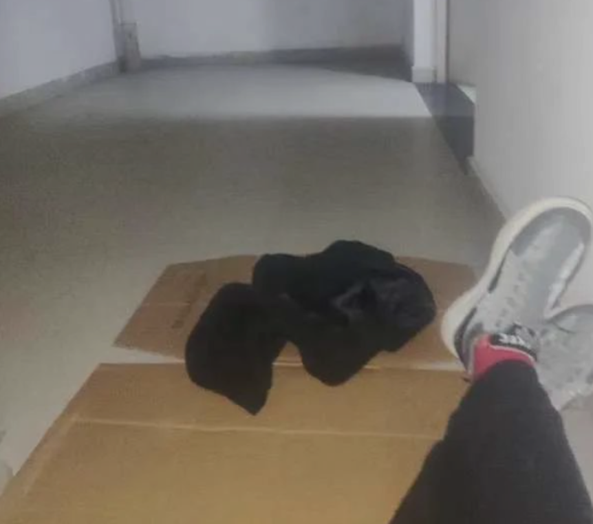 在商场楼梯间里，废纸板就是“床铺
